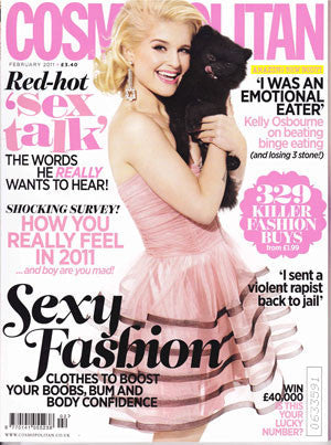 Cosmopolitan cover featuring a blonde woman in a pale pink strapless dress holding a black cat against a white background