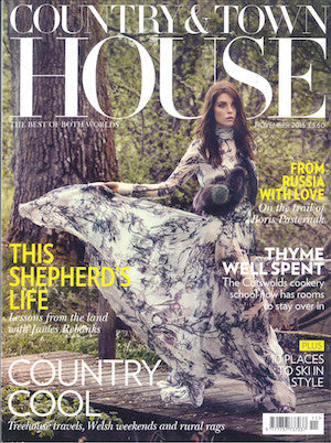 Woman seated outdoors by a tree wearing a long, flowing floral dress with full skirt spread around her