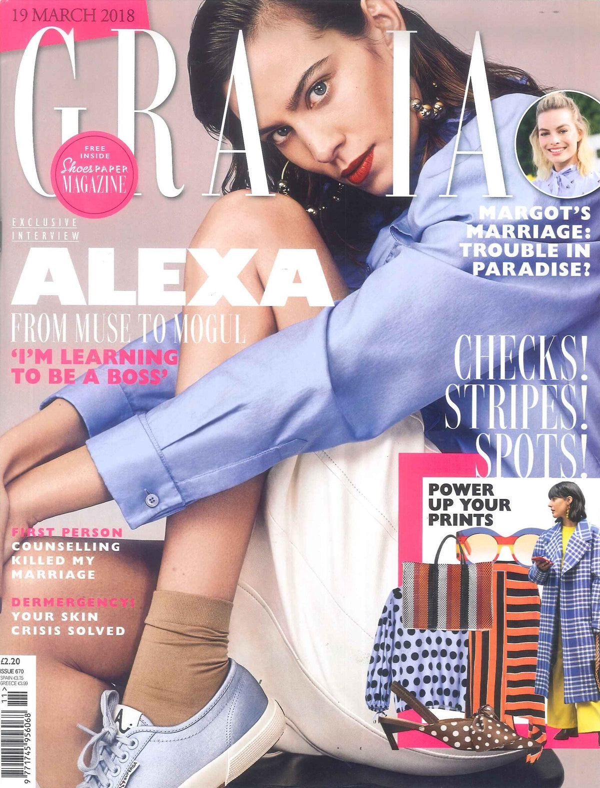 Close-up of a young woman seated curled up wearing a light blue shirt, beige socks, and grey sneakers with red lipstick