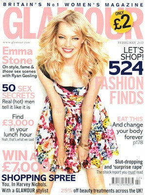 Blonde woman in a vibrant floral dress smiling and holding her skirt against a white background on a magazine cover