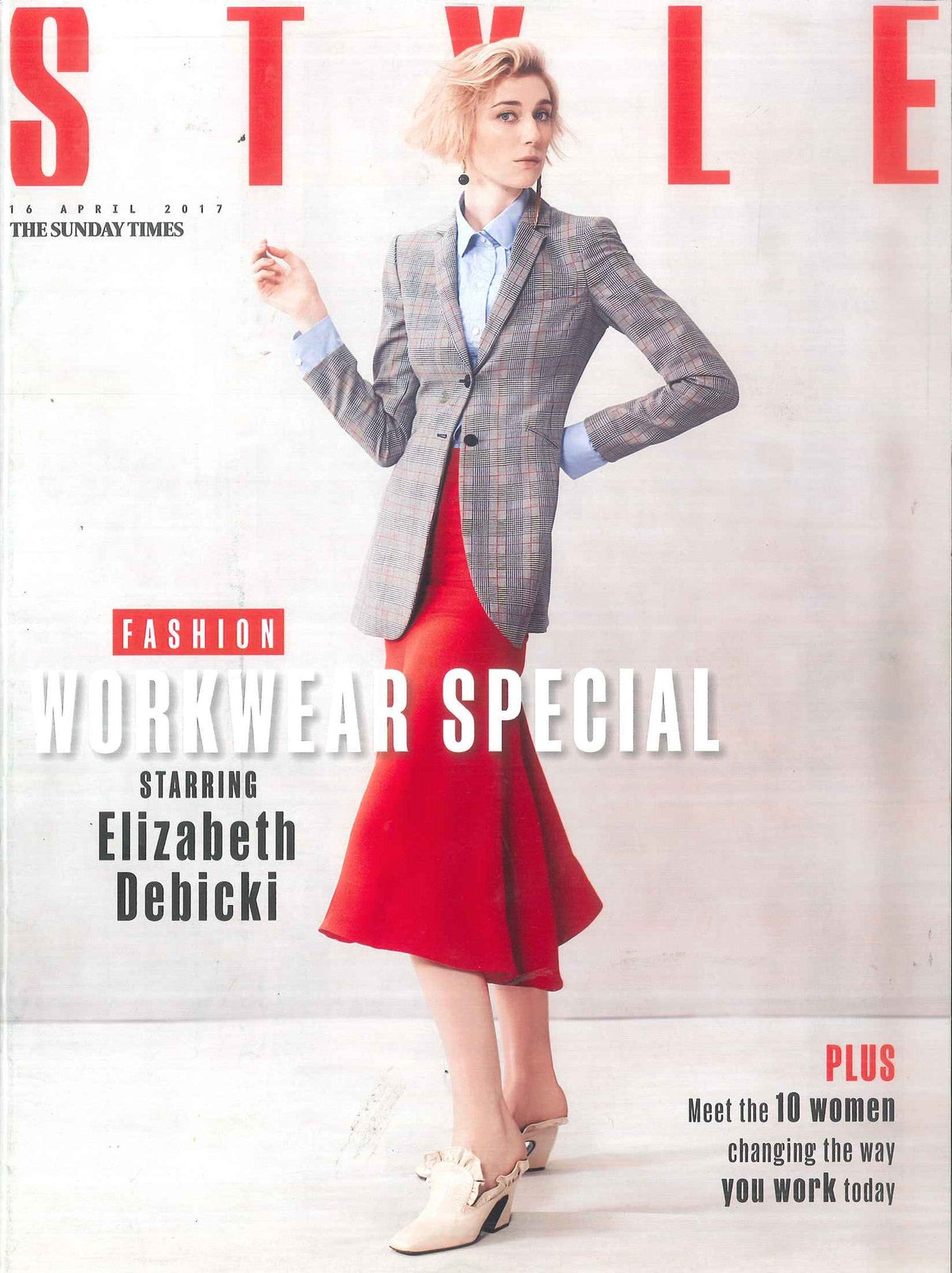 Woman wearing a checked blazer over a light blue blouse with a bright red flared skirt and white heeled shoes with ruffles